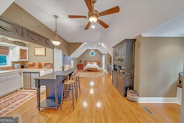 kitchen featuring a kitchen breakfast bar, ceiling fan, dishwasher, white cabinetry, and lofted ceiling