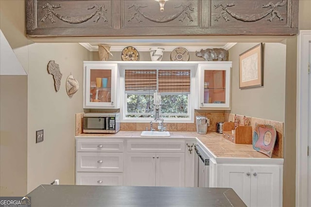 kitchen featuring stainless steel microwave, white cabinets, glass insert cabinets, and a sink