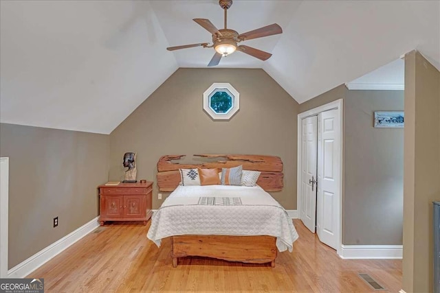 bedroom featuring light wood finished floors, baseboards, lofted ceiling, and a ceiling fan