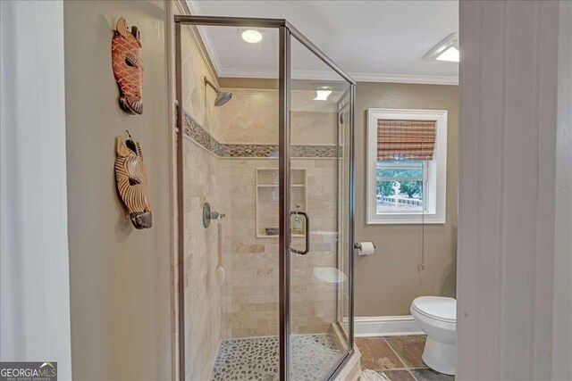 bathroom with toilet, baseboards, a stall shower, and ornamental molding