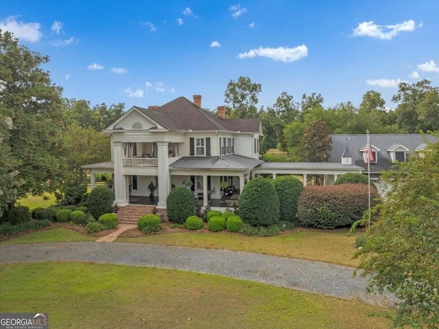 view of front of house featuring a balcony, a front lawn, and a porch