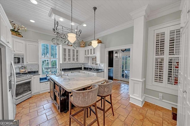 kitchen featuring tasteful backsplash, stone tile flooring, white cabinetry, stainless steel appliances, and crown molding