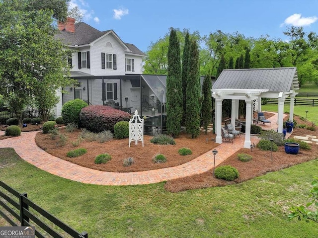 exterior space featuring a front yard, glass enclosure, and a patio area