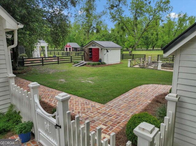 view of yard featuring an outdoor structure, fence, and a shed