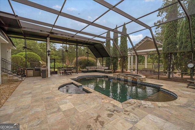 view of pool featuring glass enclosure, a patio area, a pool with connected hot tub, and an outdoor hangout area
