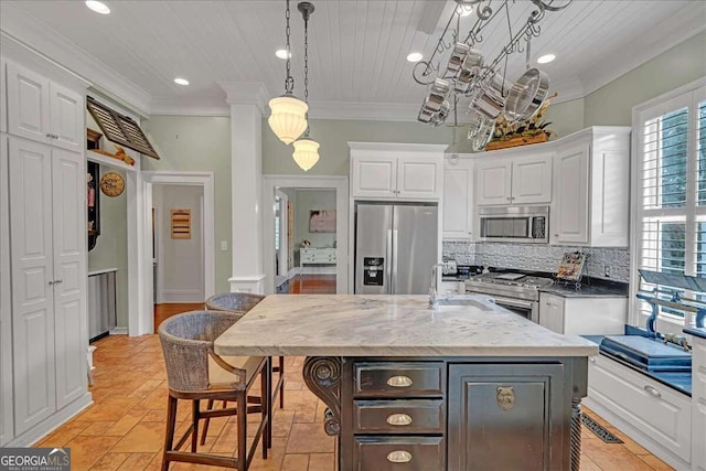 kitchen with white cabinets, backsplash, stainless steel appliances, and an island with sink