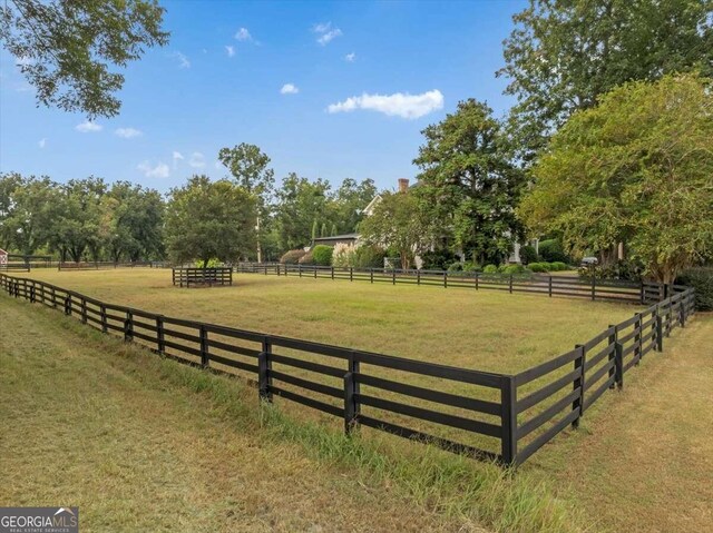 exterior space featuring a rural view, a lawn, and fence