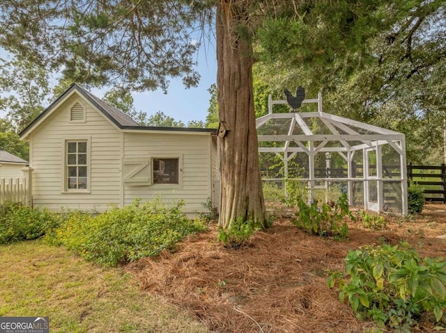 view of side of property with glass enclosure and fence