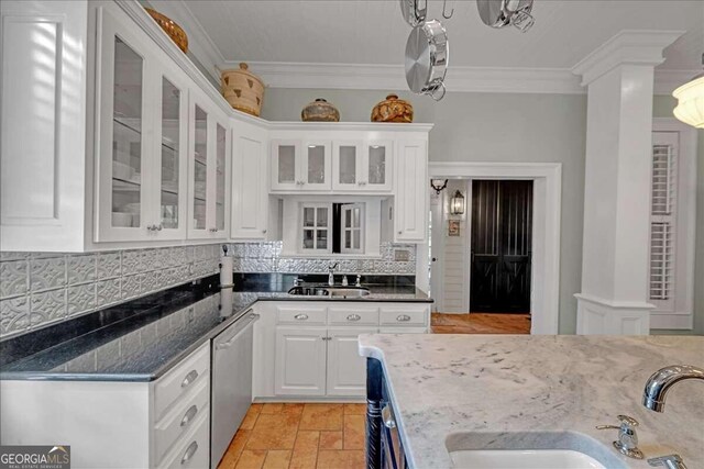 kitchen featuring stainless steel dishwasher, dark stone countertops, white cabinetry, and sink