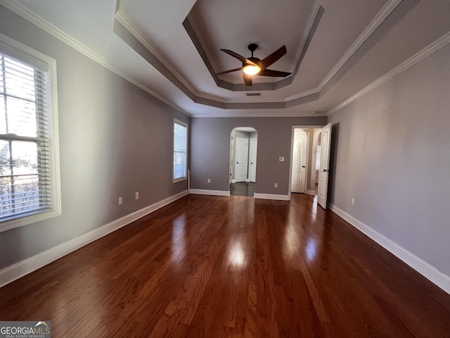 empty room featuring ceiling fan, a healthy amount of sunlight, crown molding, and a tray ceiling