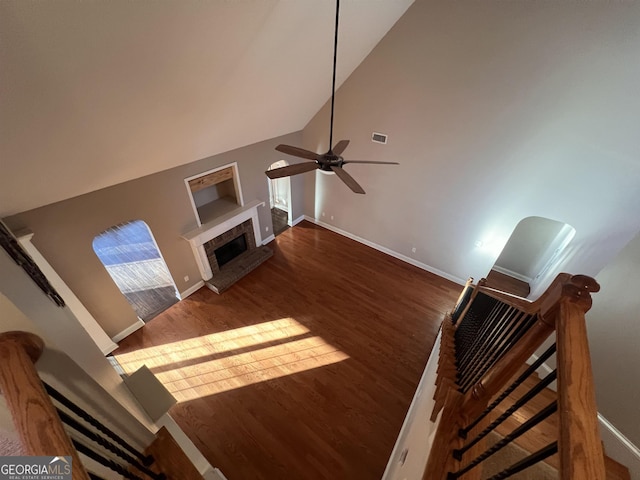 living room with ceiling fan, dark hardwood / wood-style flooring, high vaulted ceiling, and a brick fireplace