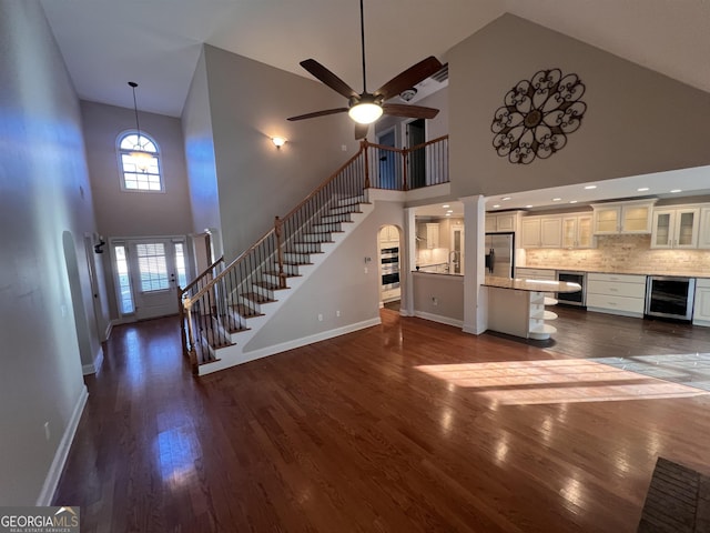 unfurnished living room featuring a high ceiling, dark hardwood / wood-style floors, and beverage cooler