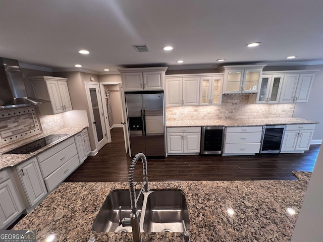 kitchen featuring white cabinetry, sink, wall chimney range hood, stainless steel fridge with ice dispenser, and black electric cooktop