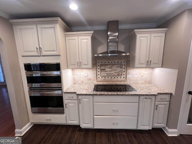 kitchen with white cabinets, black electric stovetop, stainless steel double oven, and wall chimney exhaust hood