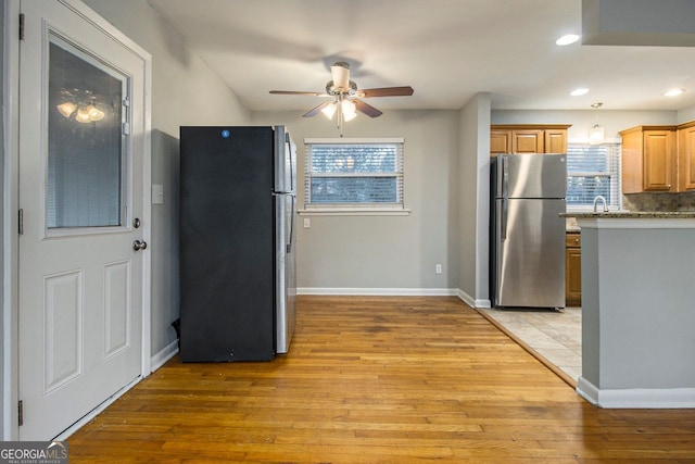 kitchen with ceiling fan, stainless steel fridge, light wood-type flooring, and tasteful backsplash