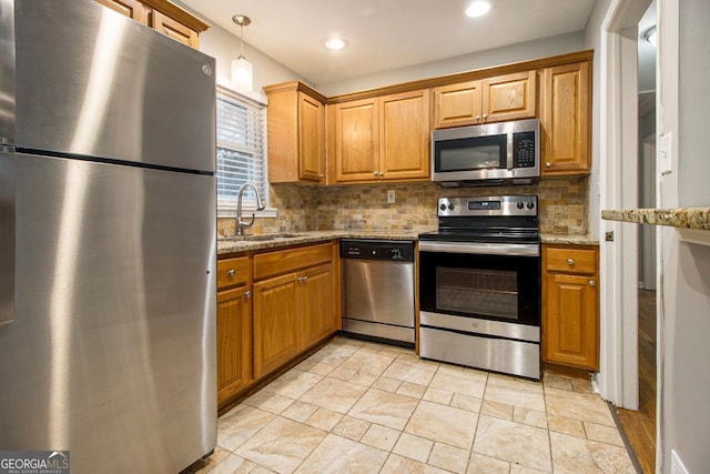 kitchen with sink, hanging light fixtures, light stone countertops, tasteful backsplash, and stainless steel appliances