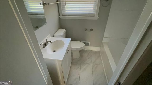 bathroom featuring a wealth of natural light, vanity, and toilet