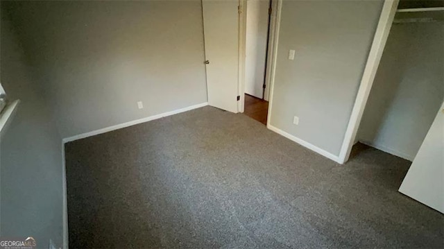 unfurnished bedroom with dark carpet and a closet