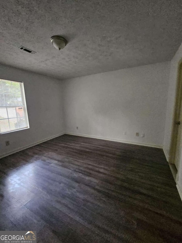 spare room with dark hardwood / wood-style flooring and a textured ceiling