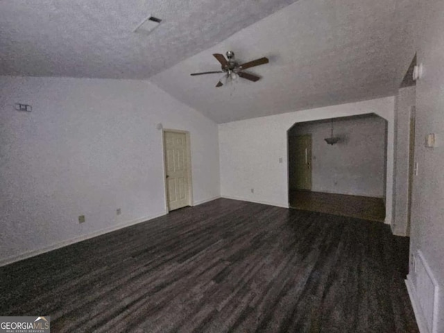 unfurnished living room featuring ceiling fan, vaulted ceiling, a textured ceiling, and dark wood-type flooring