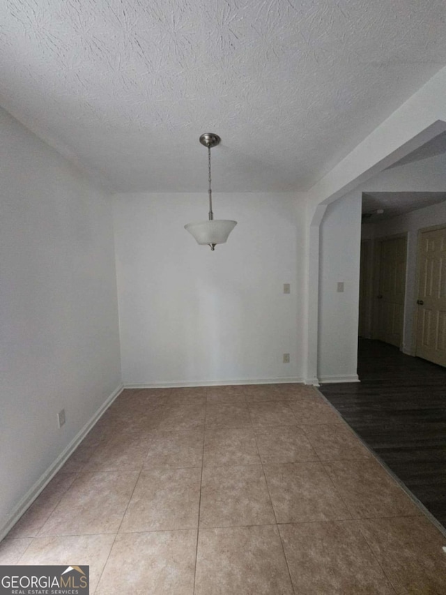 unfurnished dining area featuring tile patterned floors and a textured ceiling