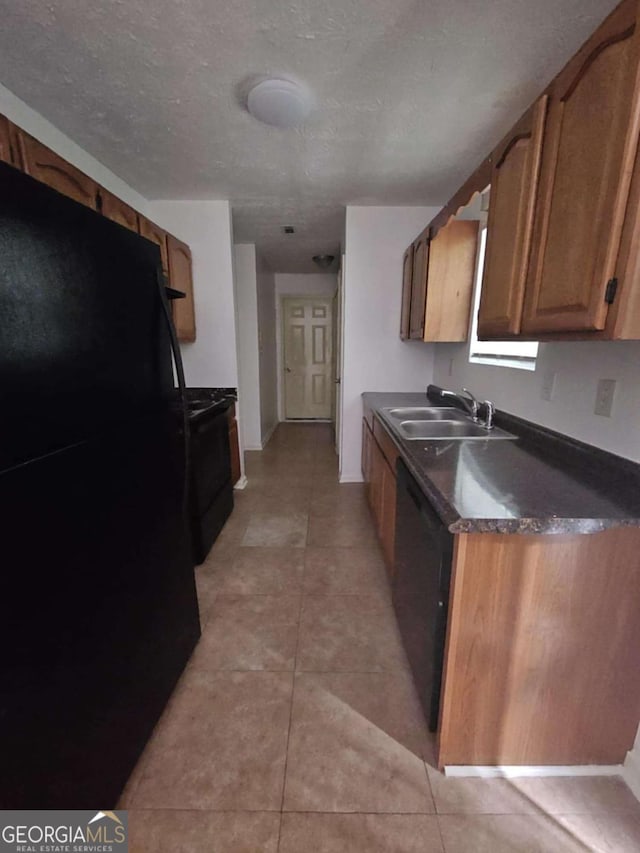 kitchen with sink, light tile patterned flooring, black appliances, and a textured ceiling