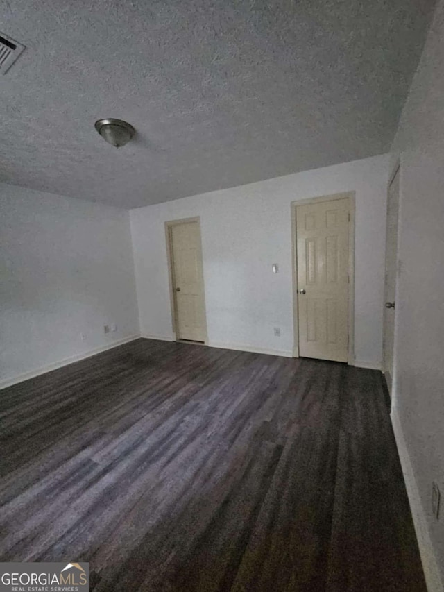 spare room with dark hardwood / wood-style floors and a textured ceiling