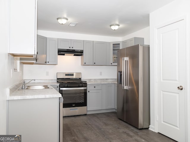 kitchen featuring appliances with stainless steel finishes, gray cabinetry, dark wood-type flooring, and sink