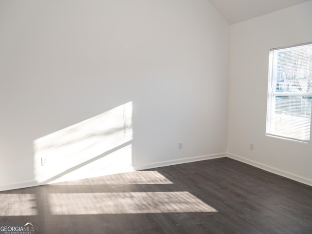 spare room with dark hardwood / wood-style flooring and vaulted ceiling