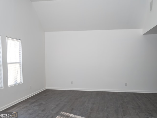 unfurnished room with dark wood-type flooring and lofted ceiling