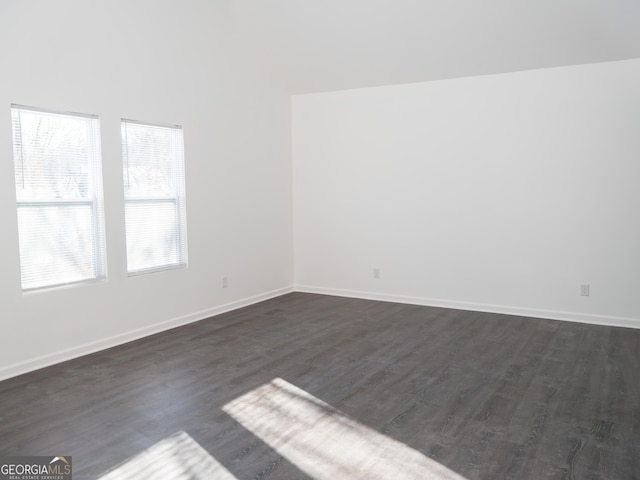 spare room with dark hardwood / wood-style flooring and a towering ceiling