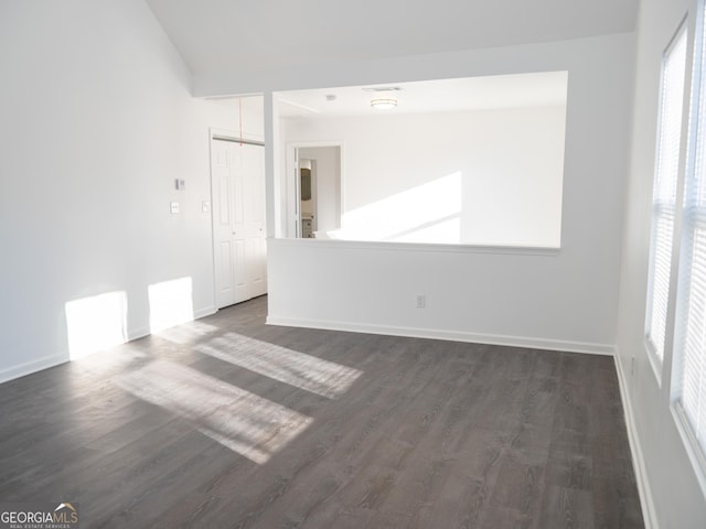 empty room with dark wood-type flooring and lofted ceiling