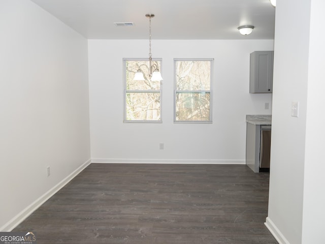 unfurnished dining area featuring a chandelier and dark wood-type flooring