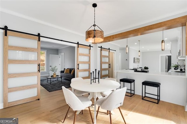 dining area with a barn door and light hardwood / wood-style floors