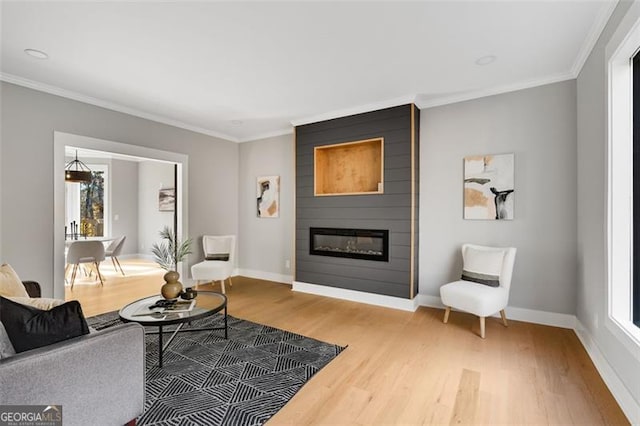 living room with crown molding, a large fireplace, and wood-type flooring