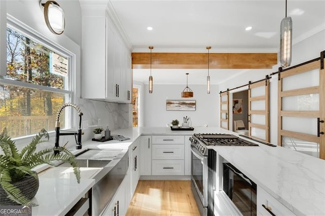 kitchen featuring white cabinets, a barn door, light stone counters, and hanging light fixtures