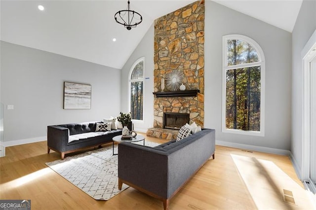 living room featuring a fireplace, light hardwood / wood-style floors, high vaulted ceiling, and a wealth of natural light