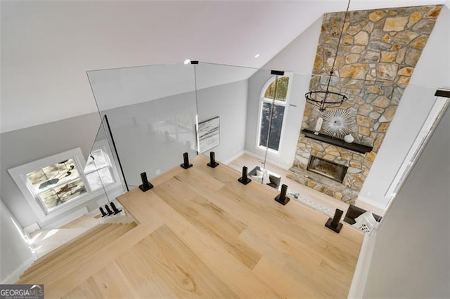 workout room featuring a stone fireplace, high vaulted ceiling, and a chandelier