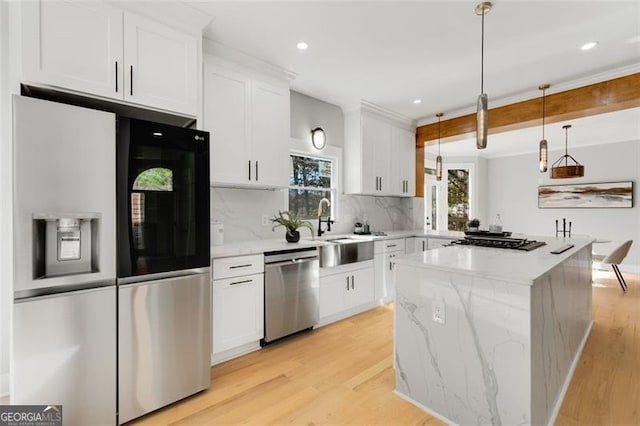 kitchen featuring light stone countertops, appliances with stainless steel finishes, light hardwood / wood-style floors, white cabinetry, and hanging light fixtures