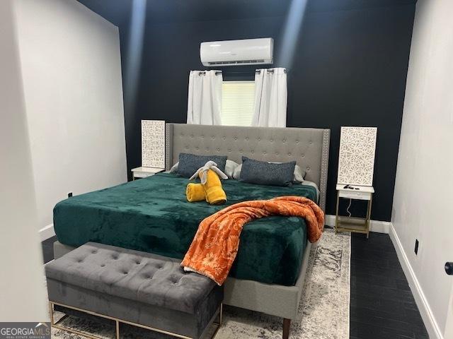 bedroom featuring an AC wall unit and dark hardwood / wood-style floors