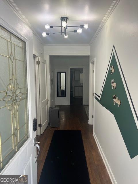 hallway featuring dark hardwood / wood-style floors, ornamental molding, and an inviting chandelier