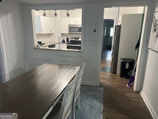 kitchen with white cabinets, appliances with stainless steel finishes, tasteful backsplash, and dark hardwood / wood-style floors