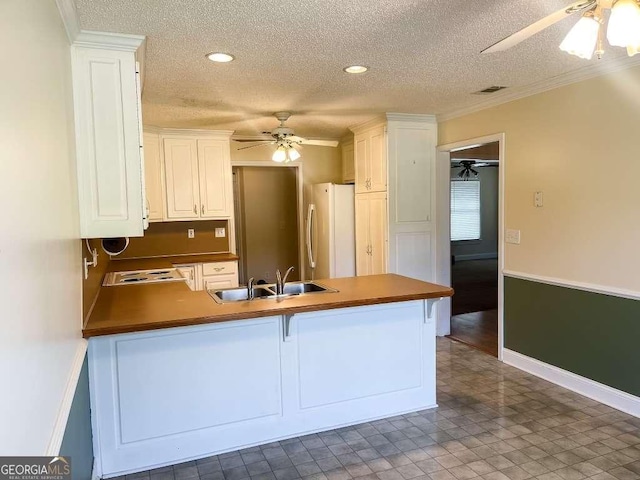 kitchen featuring white cabinets, white refrigerator, kitchen peninsula, and sink