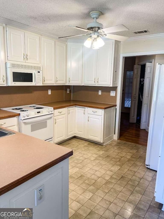 kitchen featuring white cabinets, crown molding, white appliances, and a textured ceiling