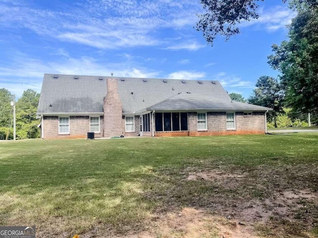 back of house featuring a sunroom and a lawn