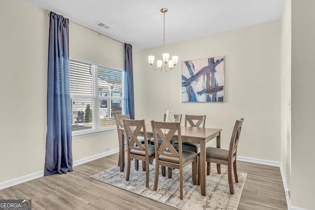 dining space featuring hardwood / wood-style floors and a notable chandelier