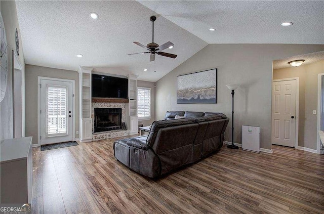 living room featuring lofted ceiling, a healthy amount of sunlight, a textured ceiling, and wood-type flooring