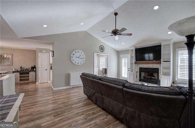 living room featuring dark hardwood / wood-style floors, a fireplace, a textured ceiling, and vaulted ceiling