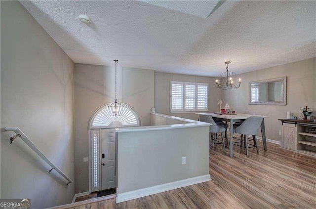 foyer entrance with a textured ceiling, hardwood / wood-style flooring, and an inviting chandelier