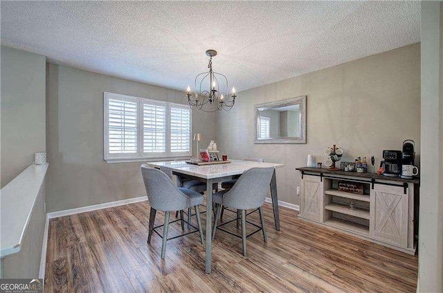 dining space featuring hardwood / wood-style floors, a textured ceiling, and a chandelier